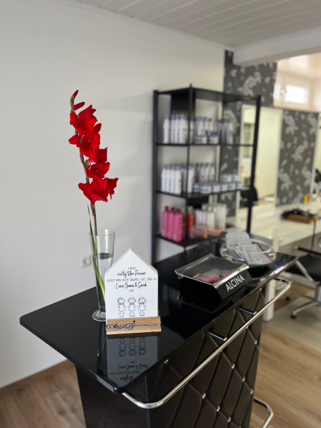 Bild des Salons: Eine Theke mit einer Blume und Willkommensschild