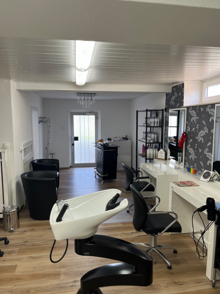 Bild des Salons: Ein Waschbecken im Vordergrund und zwei Stylingstationen im Hintergrund.