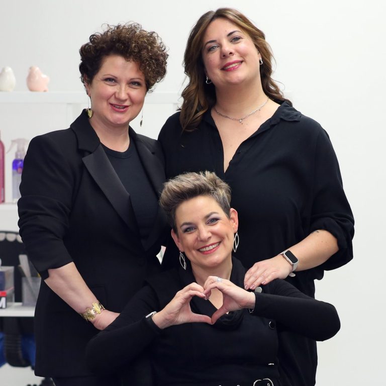 Die drei Frauen des Teams, eine formt ein Herz mit den Händen.